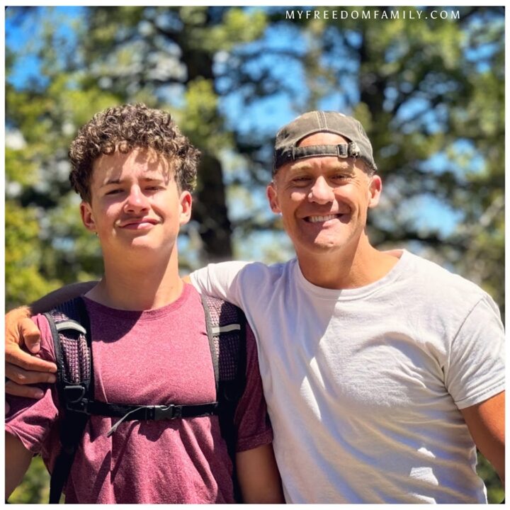 Paul Hutchings and his son standing together smiling on a camping trip