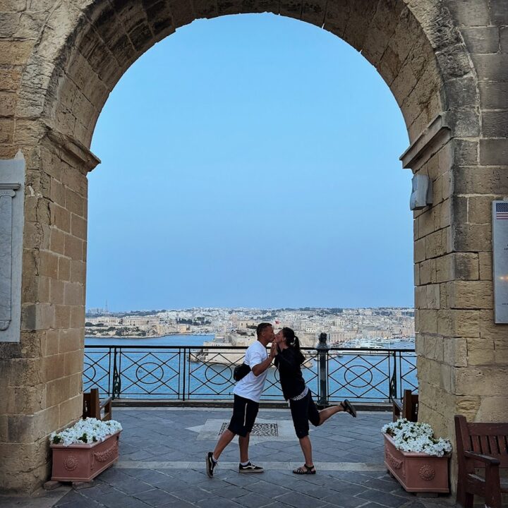 a man and woman kissing under a stone arch