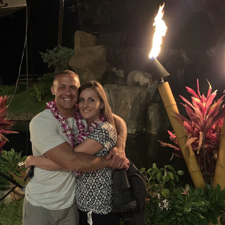 Paul and corene Hutchings hugging in front of a torch in Hawaii